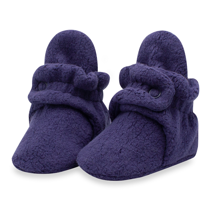 A pair of navy blue fleece baby booties with two adjustable snaps.