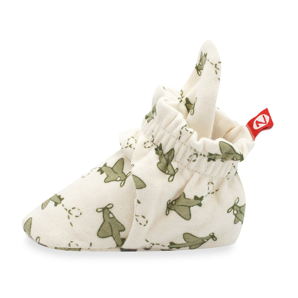 Organic cotton baby booties with gripper soles, displayed against a white background. The booties have a green airplane print on a cream base.