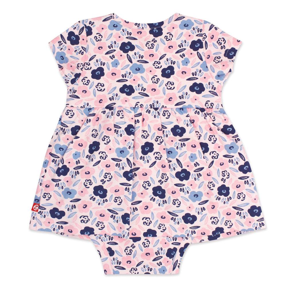 A short-sleeved romper dress for a baby girl with a blossoms print in pink, blue, and white colors.