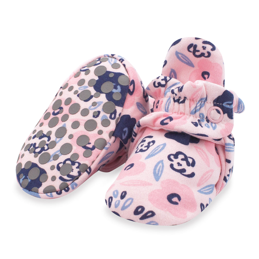 A pair of pink organic cotton baby booties with a floral and dots pattern, featuring gripper soles and a two-snap secure fit.
