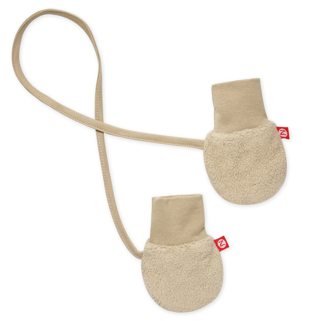 A pair of beige fleece mittens with a string attached, designed for infants.