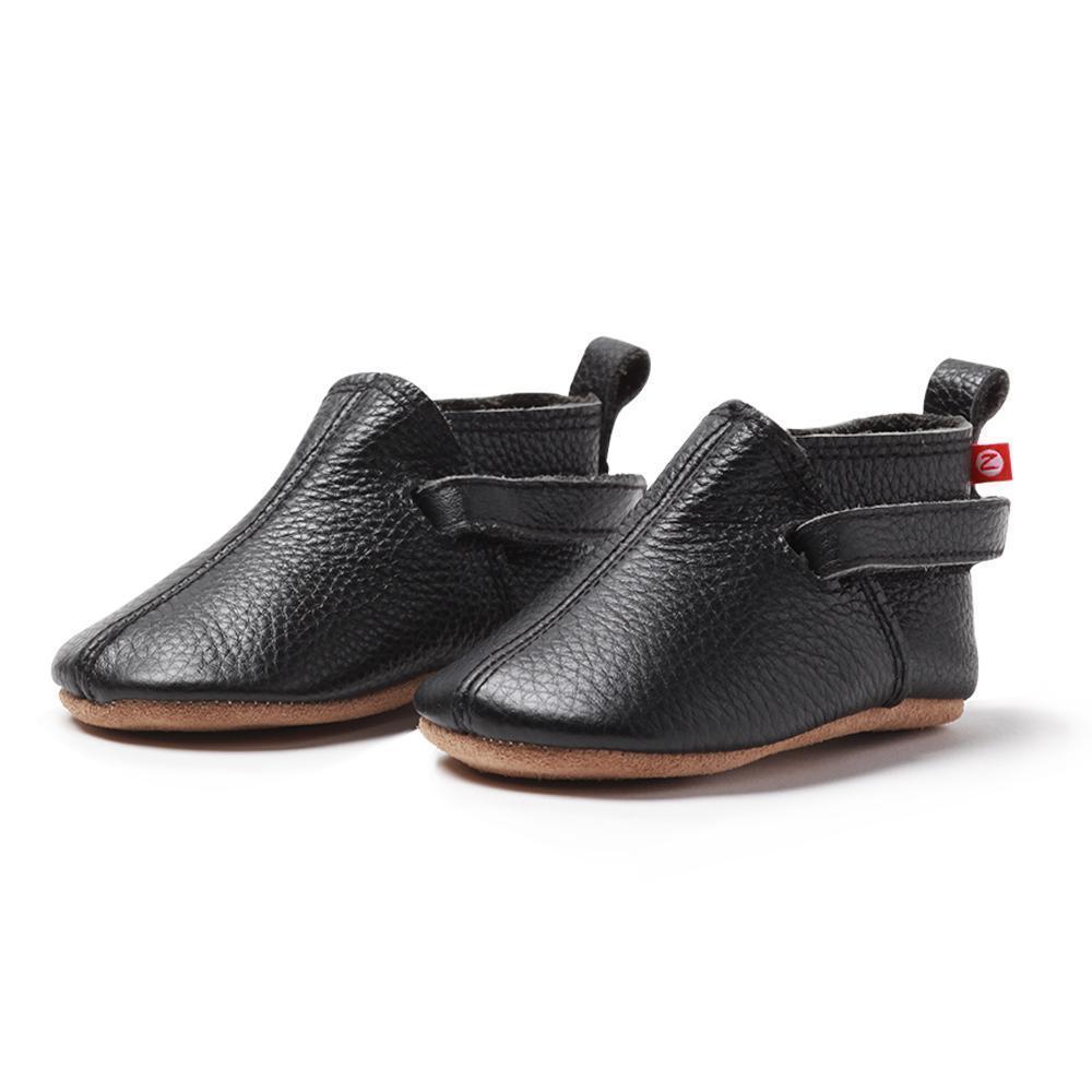 A pair of black leather baby shoes with soft soles, adjustable hook and loop straps, and a cushioned insole.