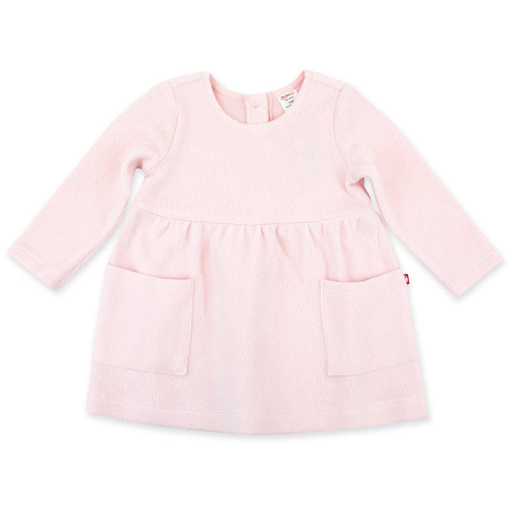 A long-sleeved baby pink fleece dress with two front patch pockets and a button opening at the back.