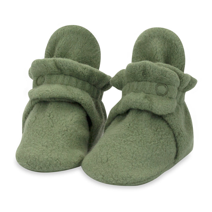A pair of olive green baby booties with two adjustable snaps on the top.