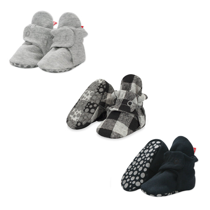 Three pairs of organic cotton baby booties in a variety of colors: gray, black, and checkered patterns, displayed against a white background.