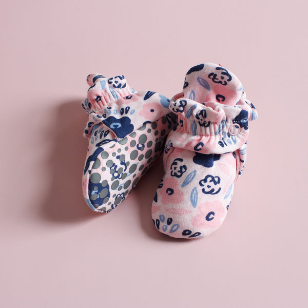 A sleeping newborn wearing Zutano organic cotton booties in a safe, clear crib environment.