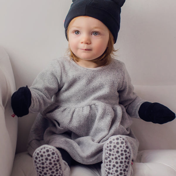 Baby in a stroller wearing Zutano fleece booties and a matching hat during a fall park outing