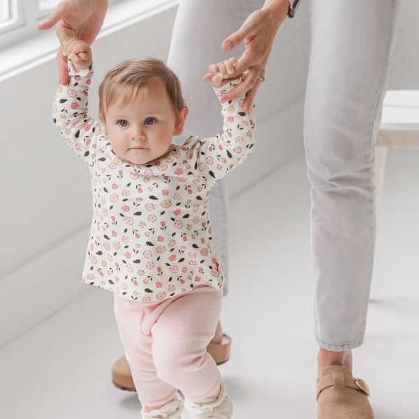 Close-up of an infant's feet in Zutano booties during the crawling and pulling-up stage, showing flexible soft-sole construction