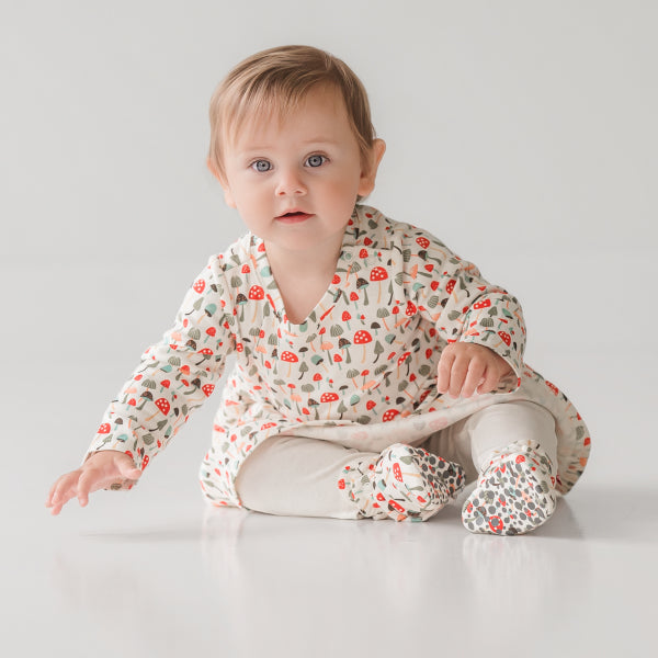 A smiling baby wearing bright, multi-colored Zutano booties and a matching organic cotton hat during playtime