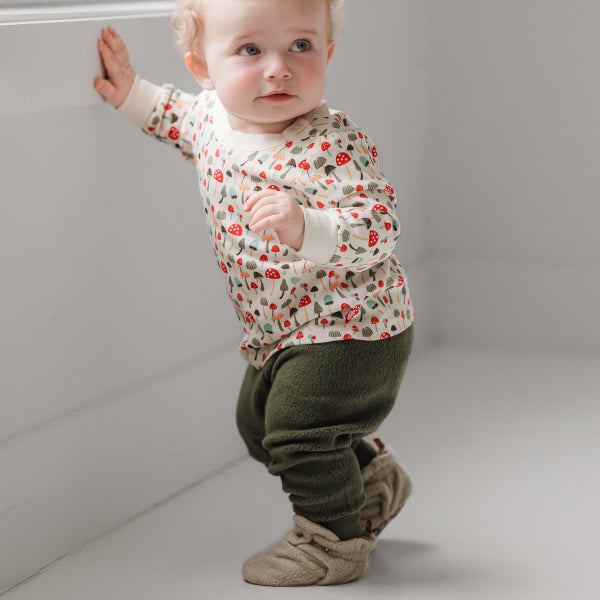 A baby wearing Zutano Sherpa-lined fleece booties during a spring walk in the park.