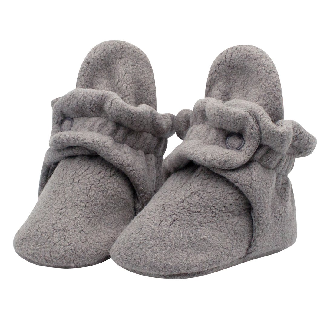 A pair of gray fleece baby booties with adjustable snaps and non-slip gripper soles.