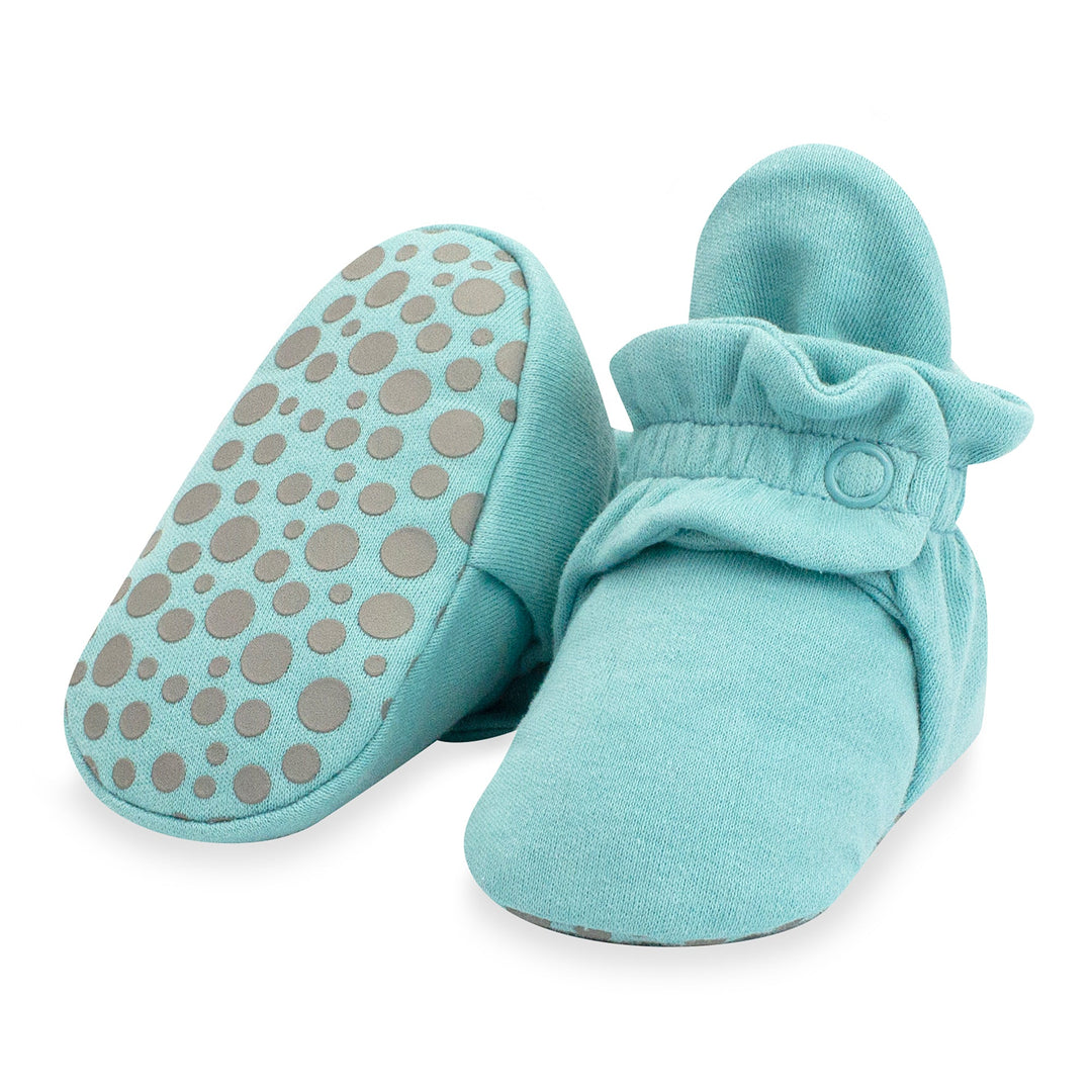 A pair of blue organic cotton baby booties with gripper dots on the bottom.