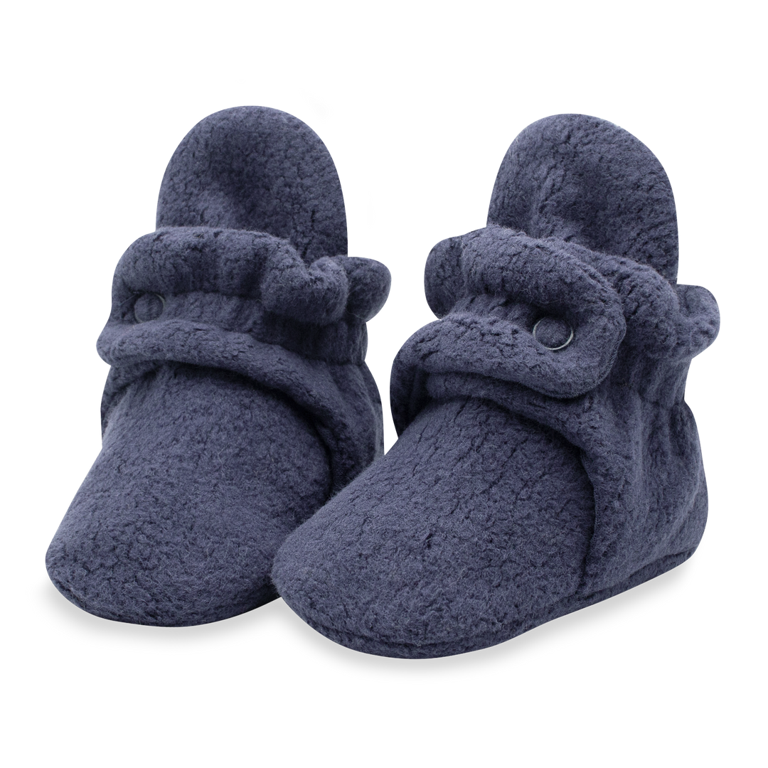 A pair of navy blue fleece baby booties with adjustable snaps.