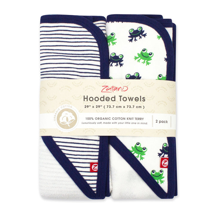 Two folded hooded towels, one with a frogs print and one with stripes, packaged together with a label indicating the product is organic cotton and includes two pieces.