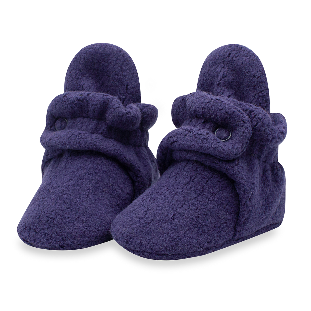 A pair of navy blue fleece baby booties with two adjustable snaps.