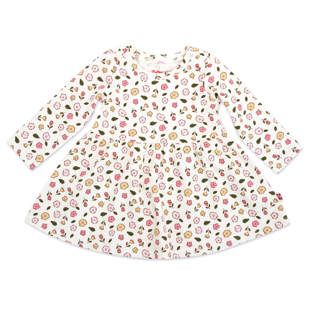 A long sleeve white organic cotton interlock dress for babies, with a floral print design consisting of yellow and pink flowers and green leaves.