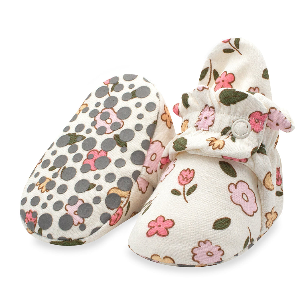 A pair of organic cotton baby booties with floral and dots patterns, featuring grippers on the bottom.