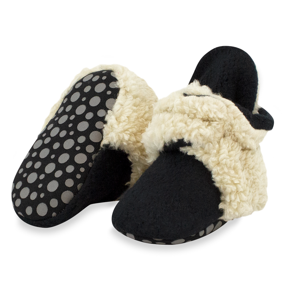 Set of black baby booties with beige furry detailing on the top and around the sole.