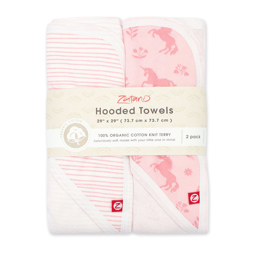 Two pink hooded towels with one featuring a unicorn print and the other a pencil stripe design, packaged together.