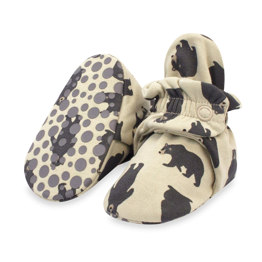A pair of organic cotton baby booties with a black bears pattern and rubber grippers on the bottom.