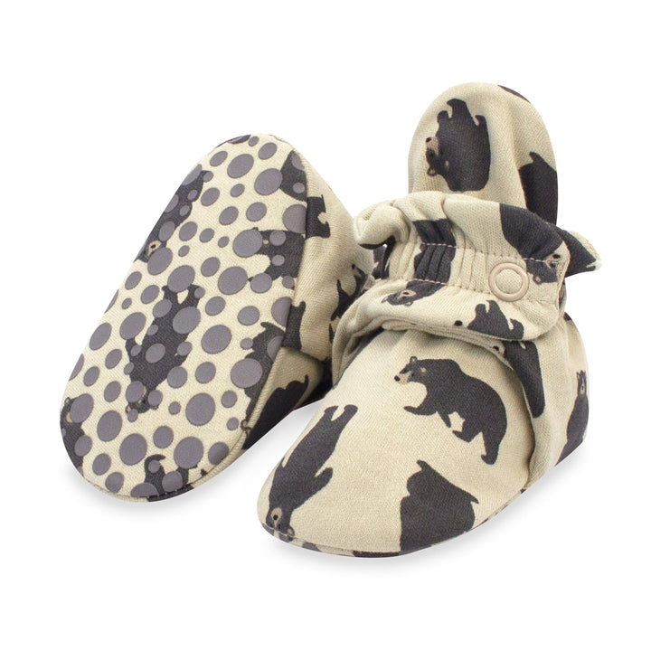 A pair of organic cotton baby booties with a black bears pattern and rubber grippers on the bottom.