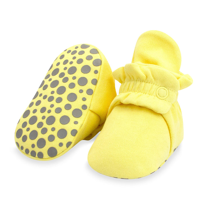 A pair of yellow organic cotton baby booties with gripper soles and a popcorn print.