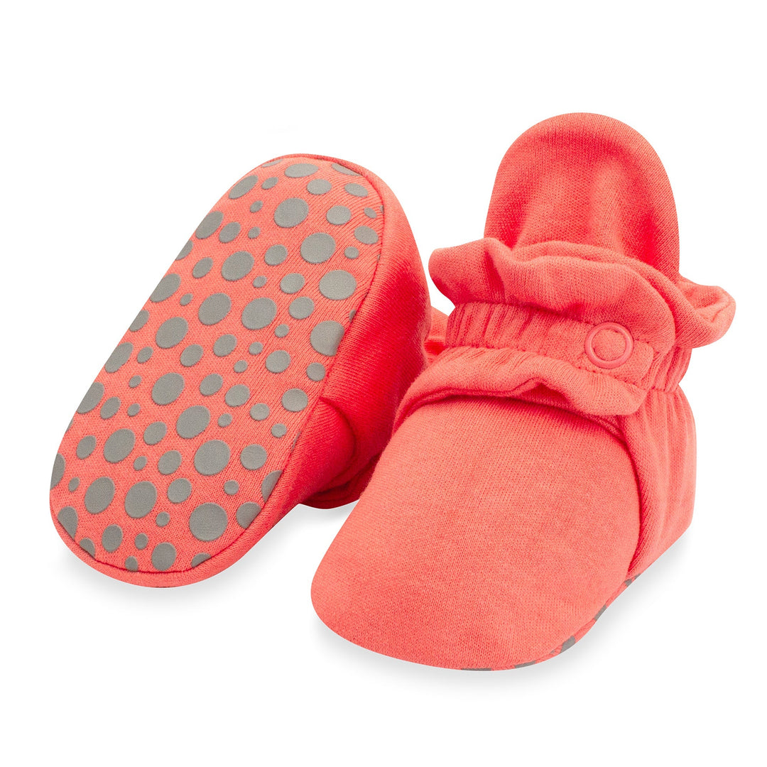 A pair of coral organic cotton baby booties with gripper soles.