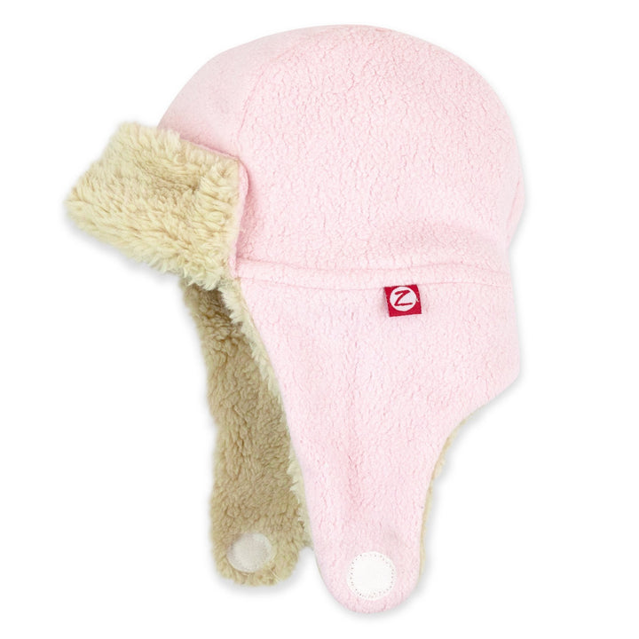 A baby pink fleece trapper hat with a soft furry lining and straps velcroing under the chin.