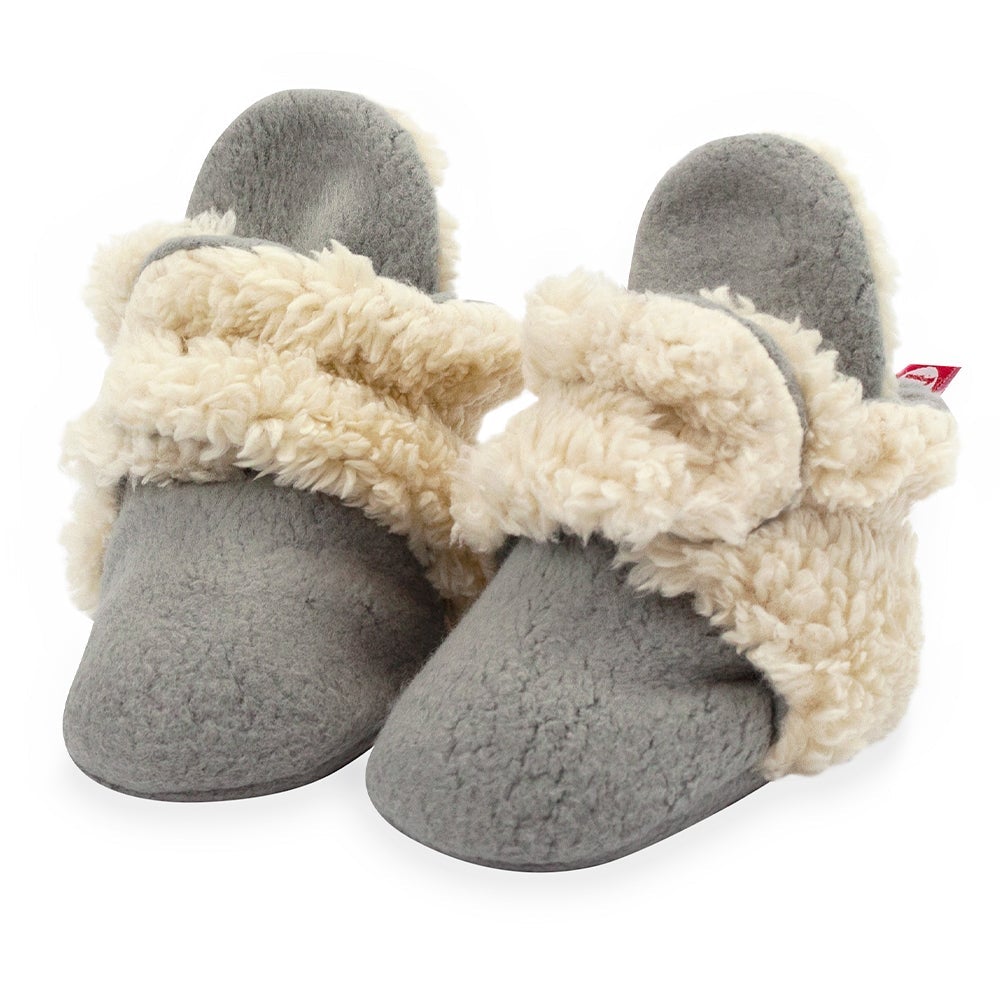 A pair of gray baby booties with beige furry trim and non-slip gripper soles.