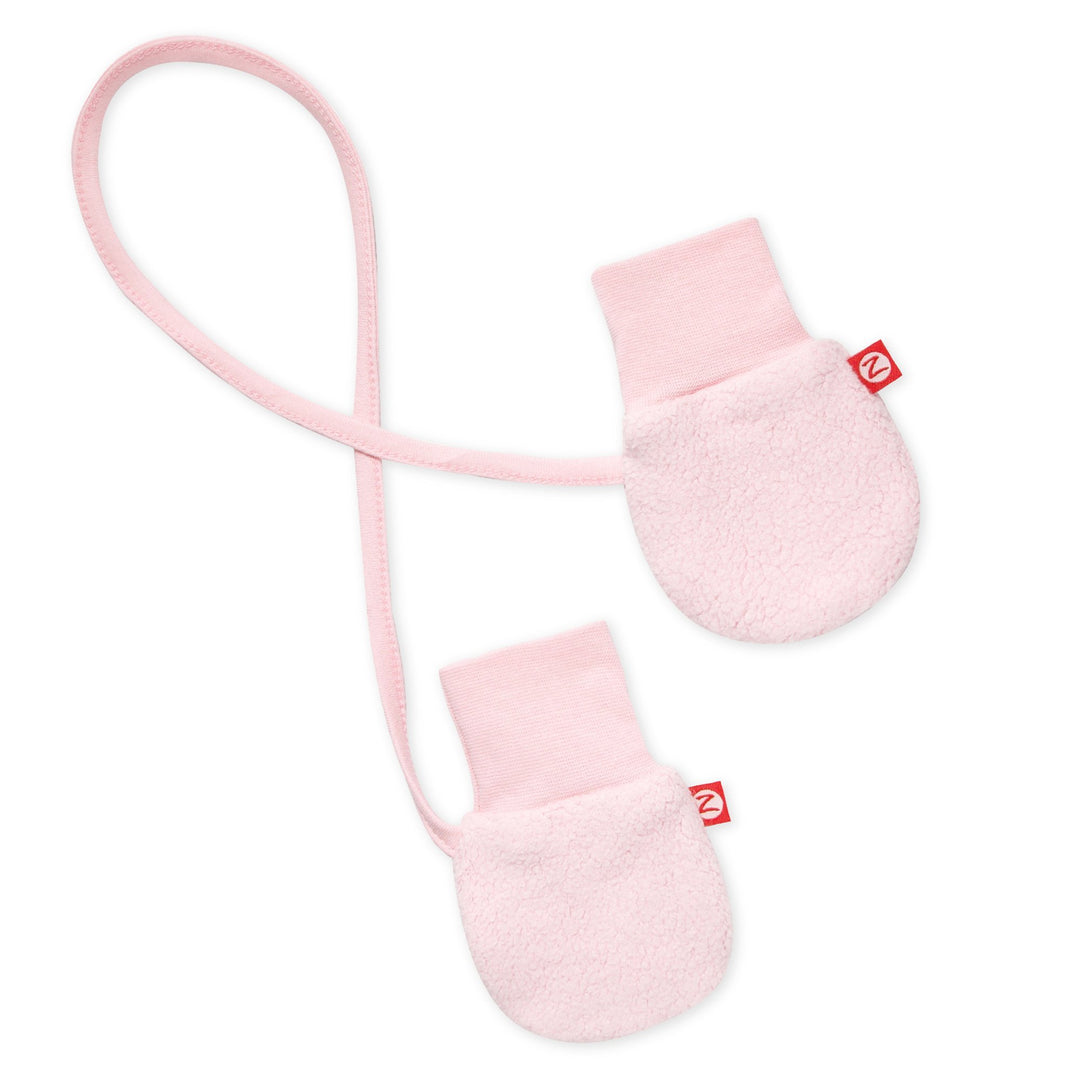 A pair of baby pink fleece mittens with a string attached, designed for infants.