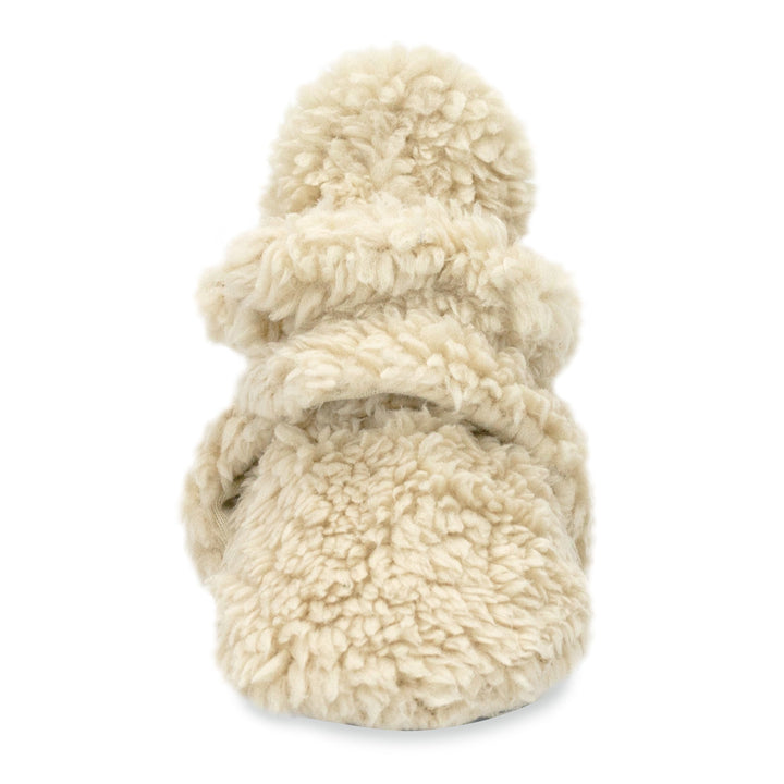 A set of beige baby booties with faux fur exterior and gripper dots on the sole.