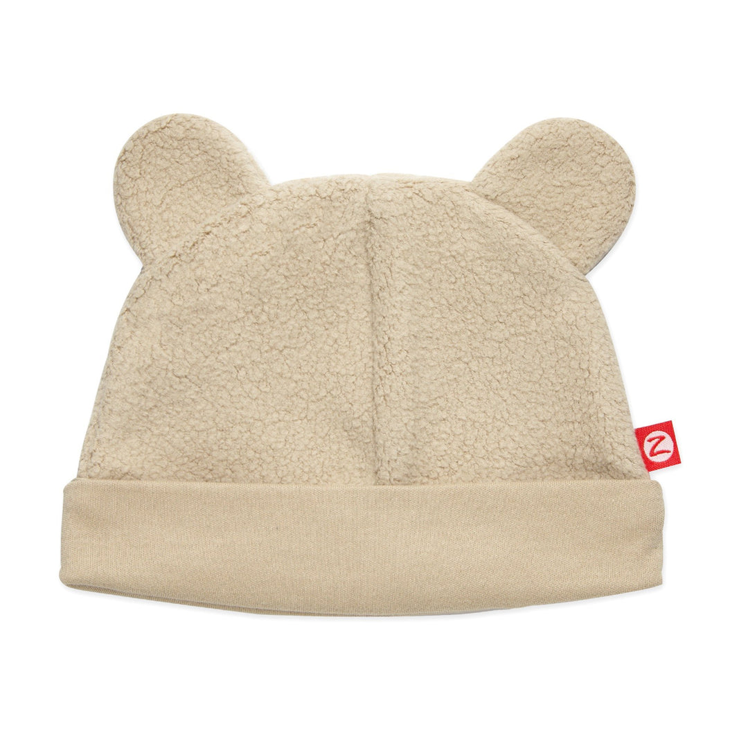 A beige fleece baby hat with ears resembling a teddy bear's face.