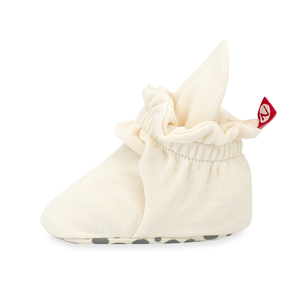 Beige organic cotton baby booties with rubber grippers on the sole.