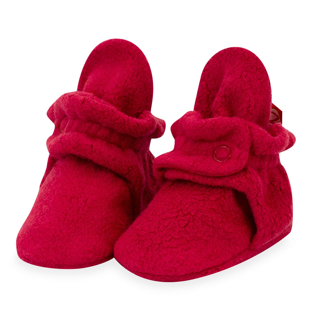 A pair of cranberry red fleece baby booties with two-snap secure fit and non-slip gripper soles.