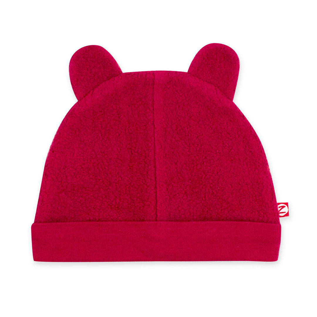 A cranberry red fleece baby hat with ears resembling a bear's face.