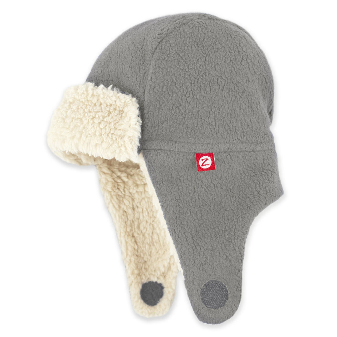 A gray fleece trapper hat with a soft furry lining and ear flaps, featuring a red logo on the front.
