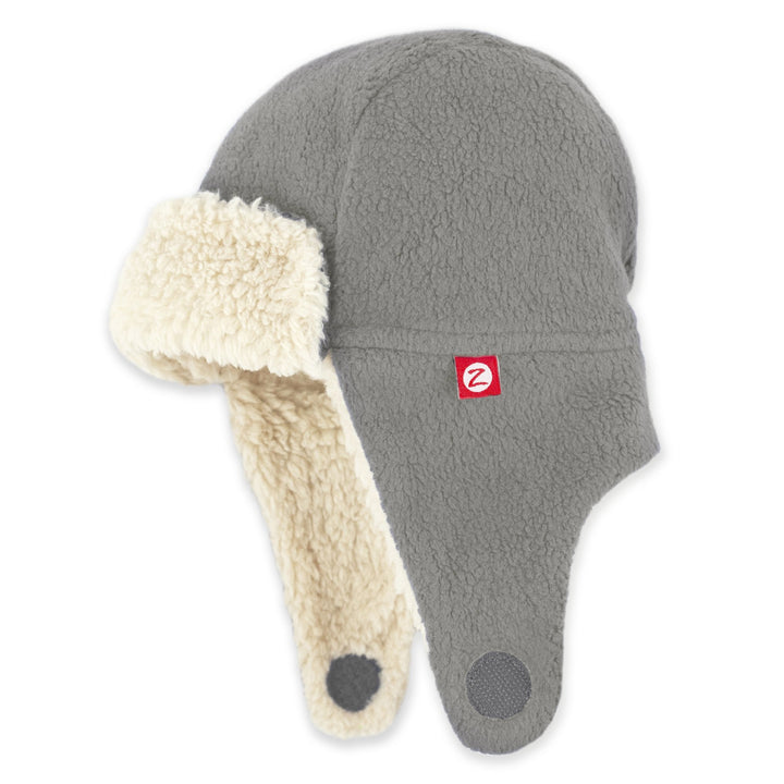 A gray fleece trapper hat with a soft furry lining and ear flaps, featuring a red logo on the front.
