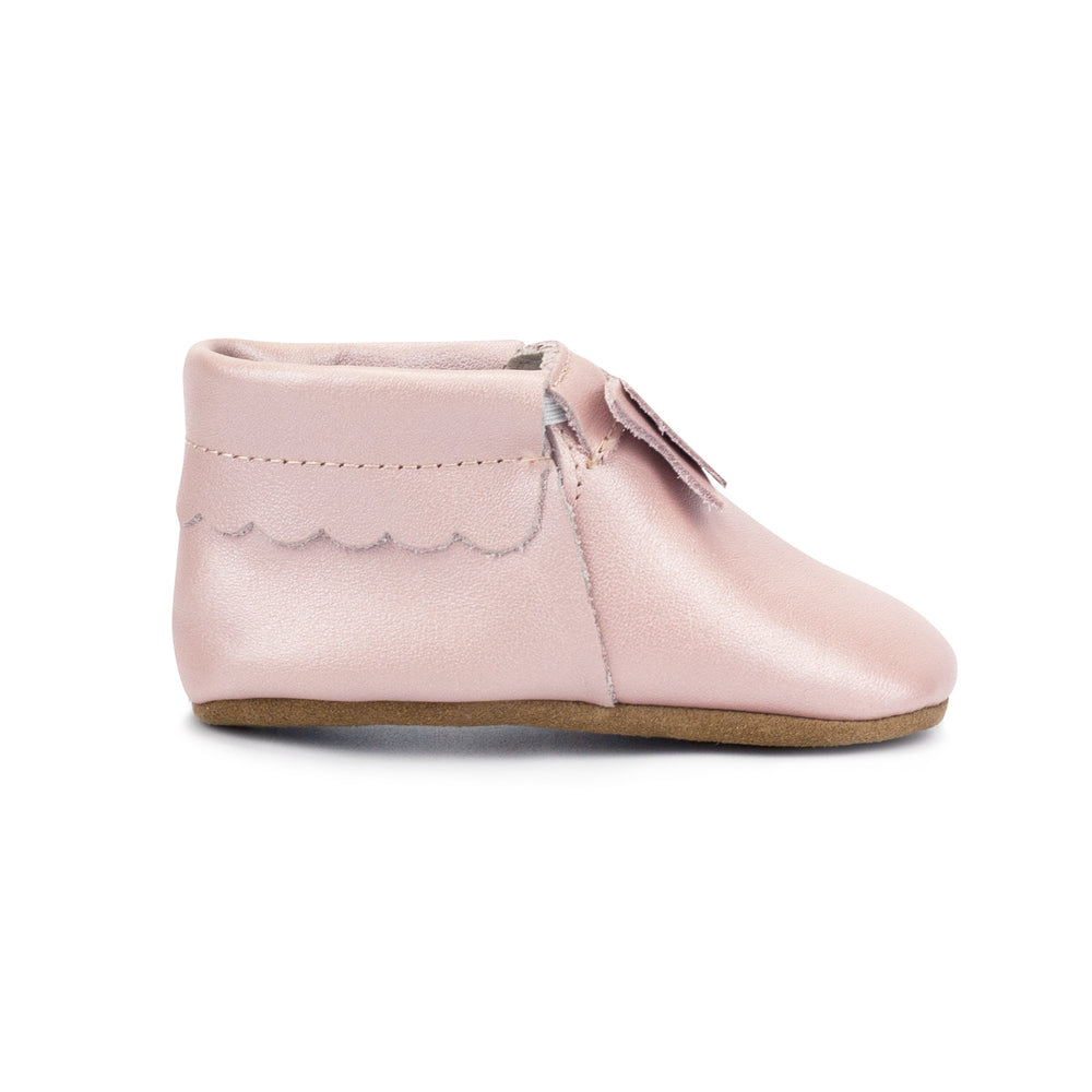 Leather baby moccasins with a bow on the tongue and a non-slip sole.