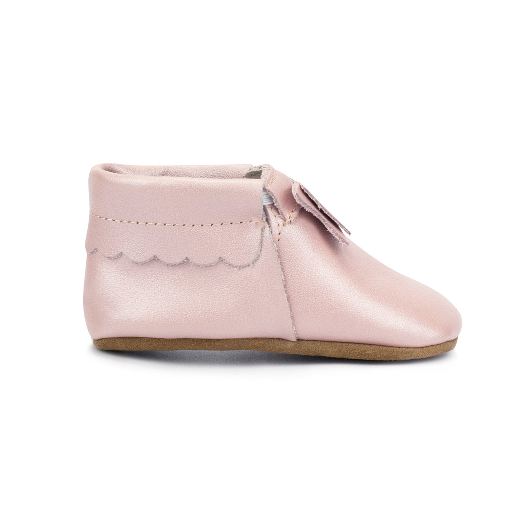 Leather baby moccasins with a bow on the tongue and a non-slip sole.