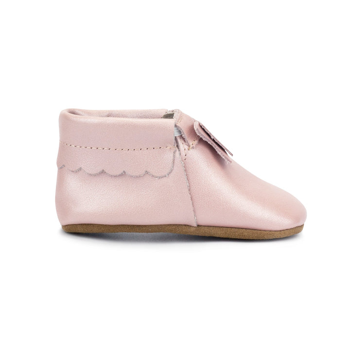 Leather baby moccasins with a bow on the tongue and a non-slip sole.