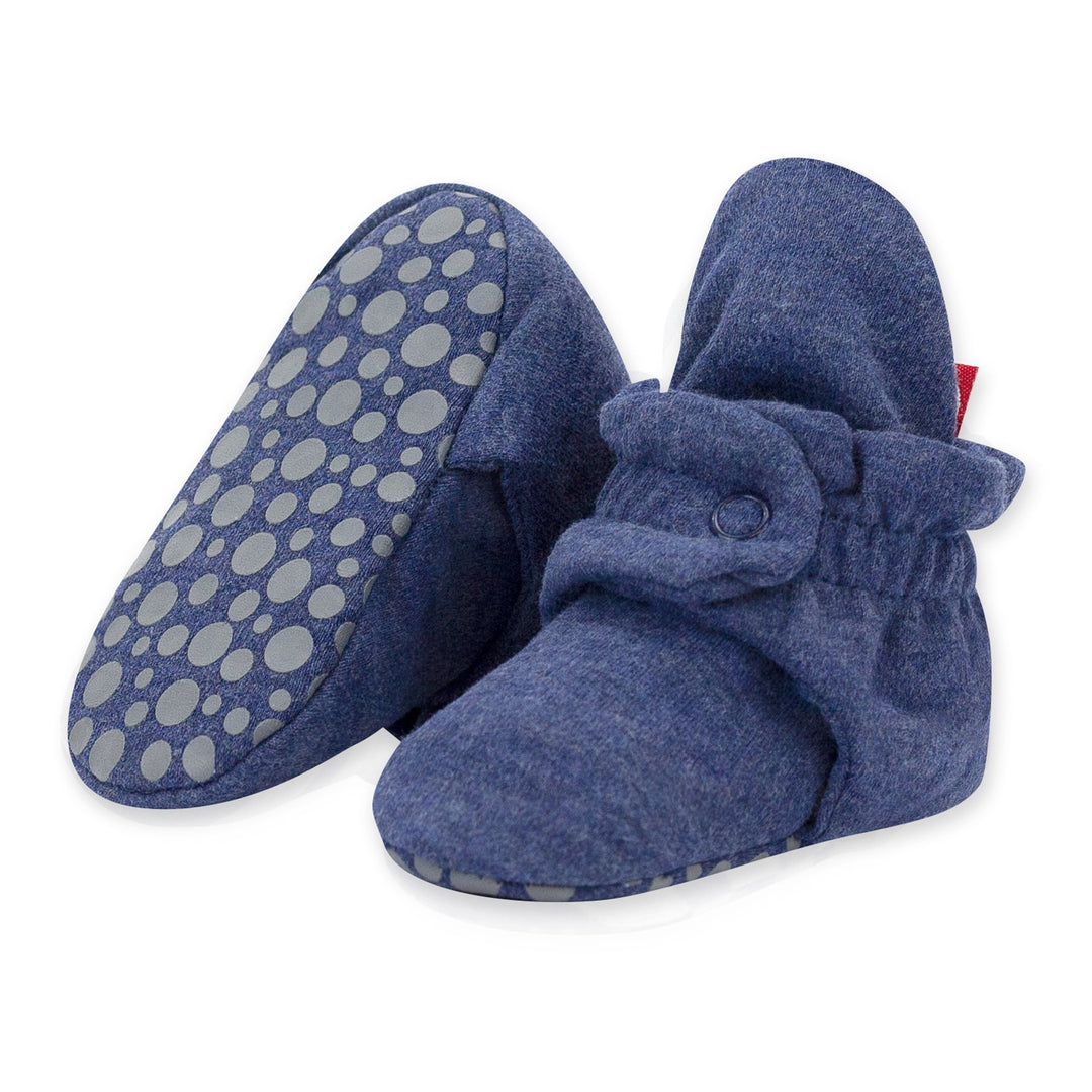 A pair of navy-colored organic cotton baby booties with rubber grippers on the sole and a two-snap secure fit.