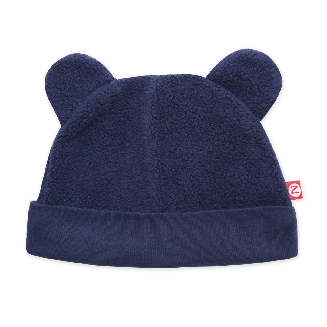 A navy blue fleece baby hat with ears resembling a bear's face.