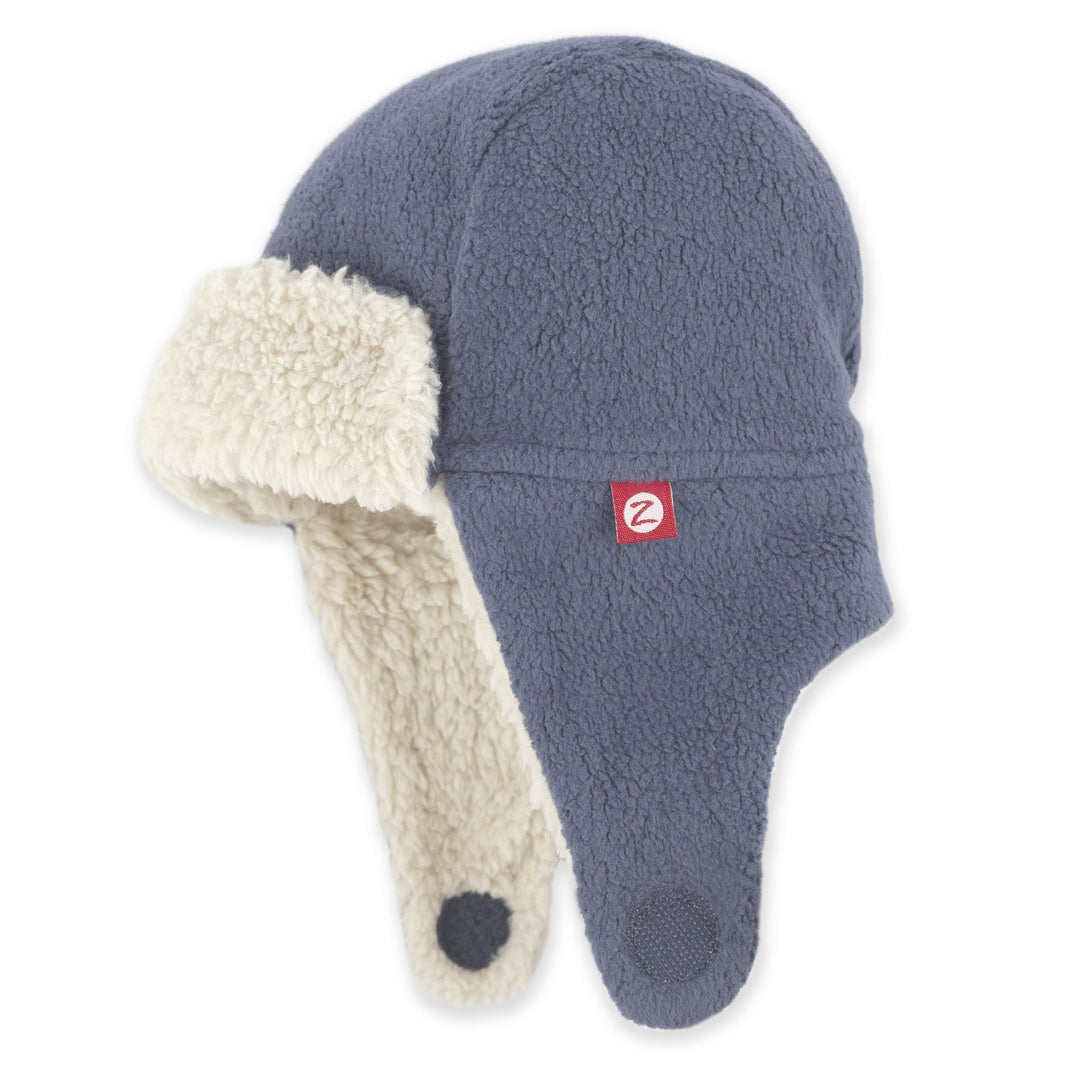 A denim navy colored fleece trapper hat with soft furry lining and earflaps, featuring a velcro strap under the chin.