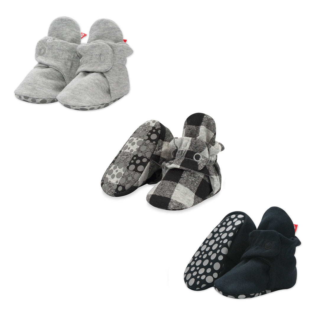 Three pairs of organic cotton baby booties in a variety of colors: gray, black, and checkered patterns, displayed against a white background.