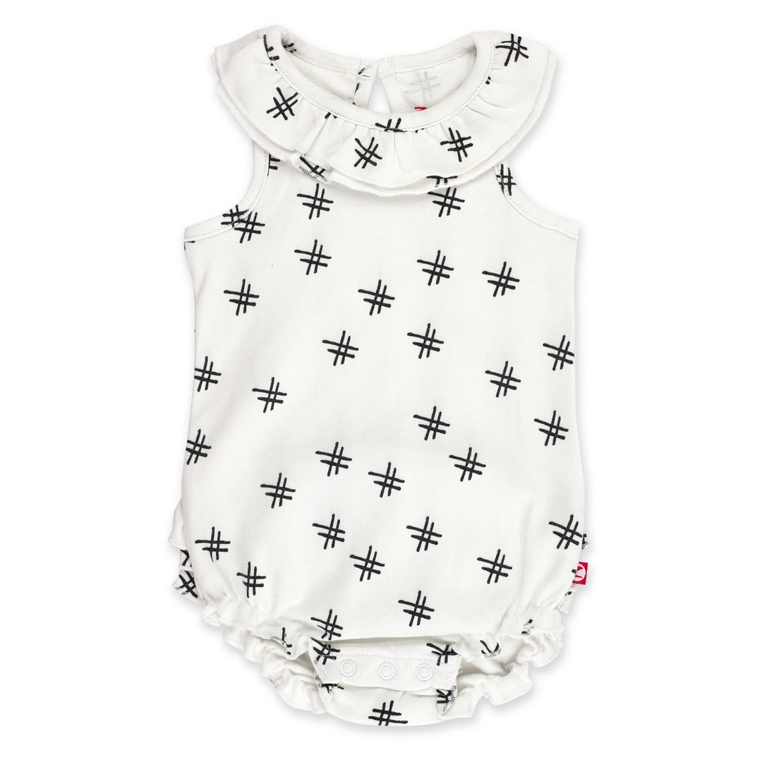 A white organic cotton ruffle romper for babies with a hashtag print, featuring a ruffled collar and bottom, keyhole opening at the back, and snaps between the legs.
