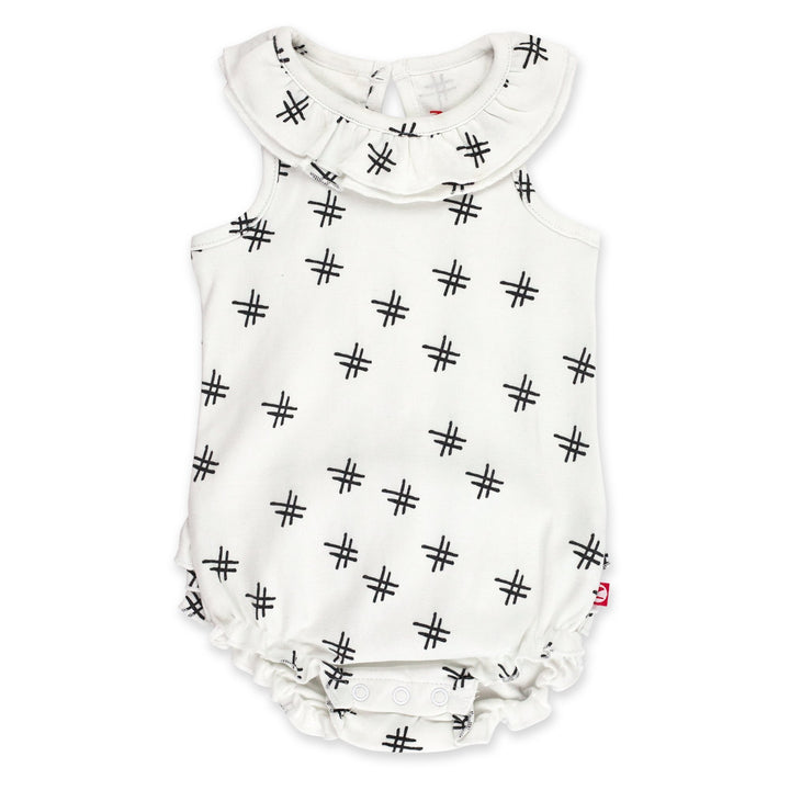 A white organic cotton ruffle romper for babies with a hashtag print, featuring a ruffled collar and bottom, keyhole opening at the back, and snaps between the legs.
