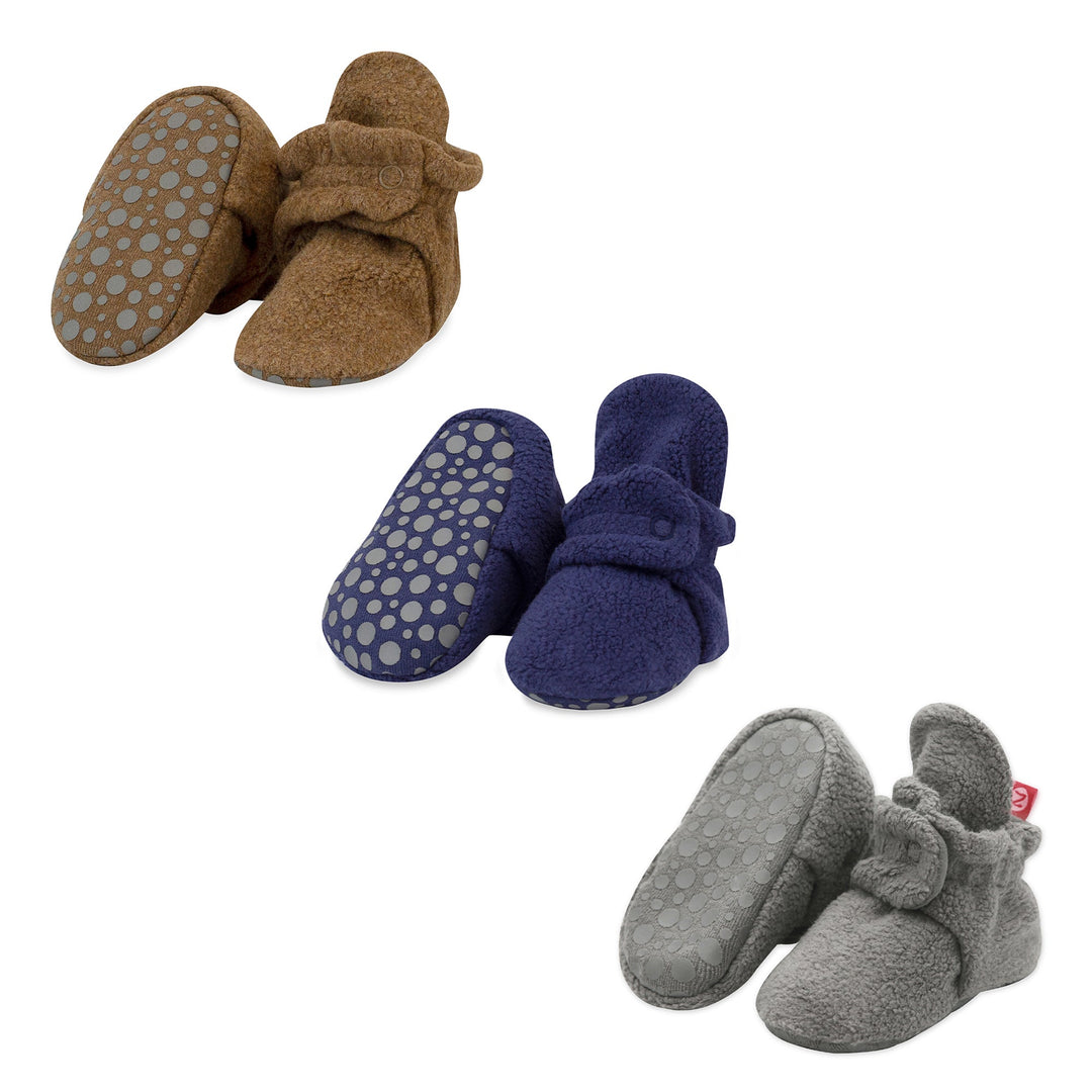 Three pairs of fleece baby booties in heather mocha, true navy, and gray, each pair with a textured gripper sole.