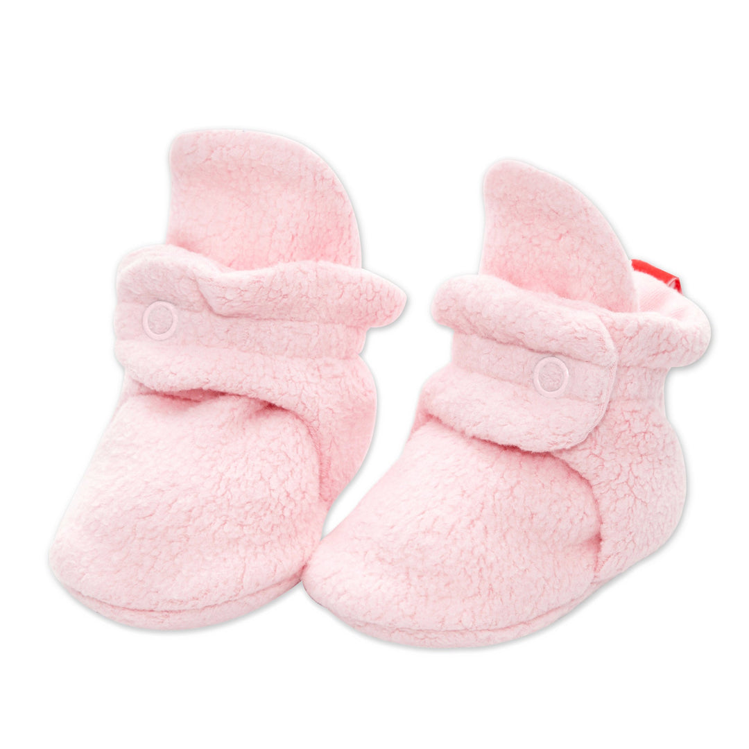 A pair of pink baby booties with two adjustable snaps and non-slip gripper soles.