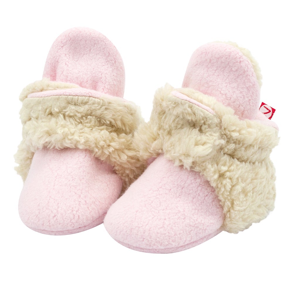 A pair of pink baby booties with white furry trim and non-slip gripper soles.