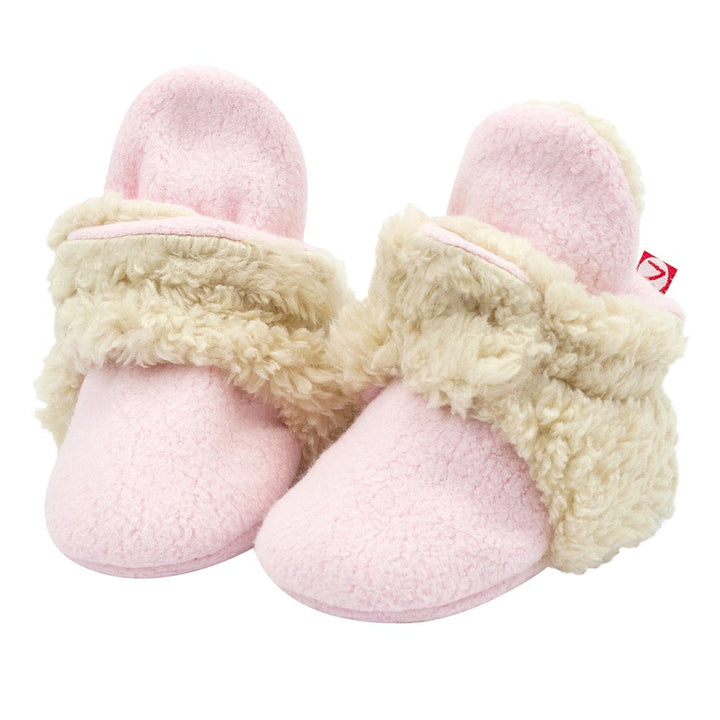 A pair of pink baby booties with white furry trim and non-slip gripper soles.
